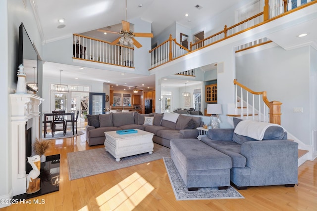 living room featuring crown molding, high vaulted ceiling, ceiling fan with notable chandelier, and light hardwood / wood-style floors