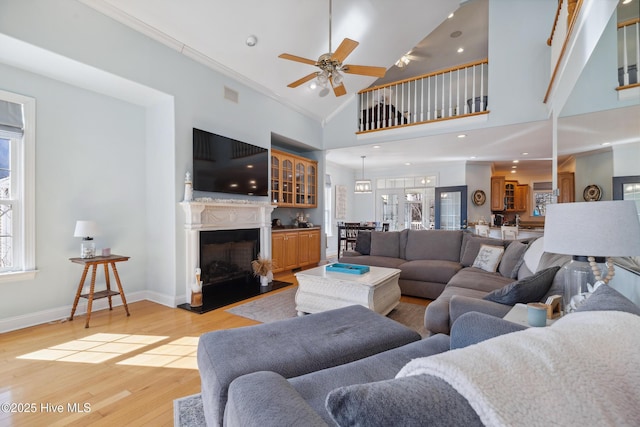 living room featuring crown molding, ceiling fan, high vaulted ceiling, and light wood-type flooring