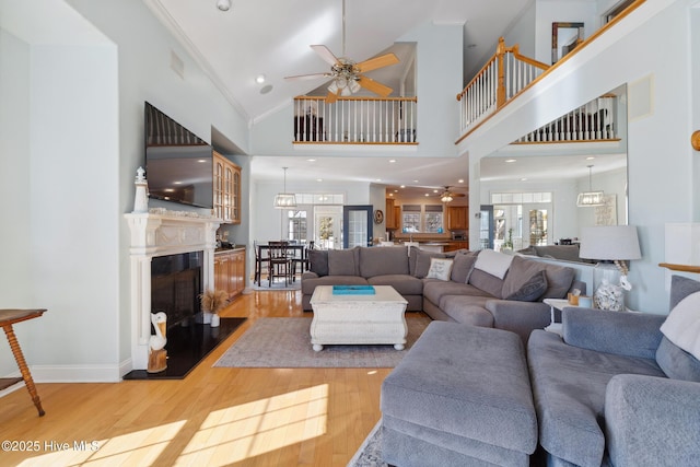 living room featuring hardwood / wood-style floors, crown molding, high vaulted ceiling, and ceiling fan