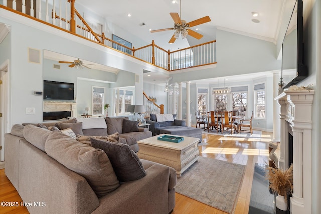 living room with a high ceiling, decorative columns, ceiling fan, and light hardwood / wood-style flooring