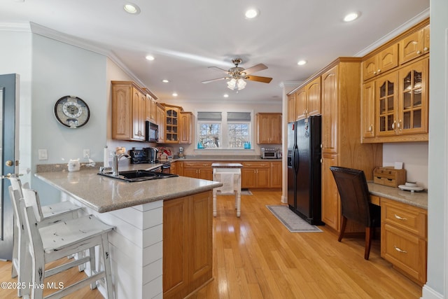 kitchen featuring built in desk, kitchen peninsula, sink, a kitchen bar, and black appliances