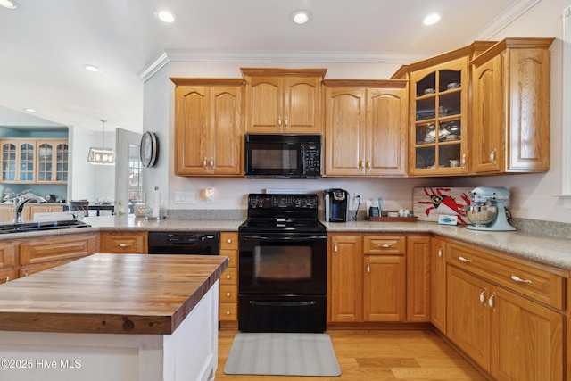 kitchen with butcher block countertops, sink, crown molding, hanging light fixtures, and black appliances