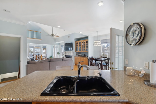 kitchen featuring lofted ceiling, sink, crown molding, pendant lighting, and ceiling fan