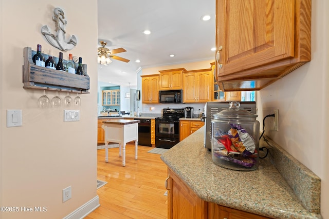 kitchen featuring crown molding, ceiling fan, light stone counters, black appliances, and light wood-type flooring