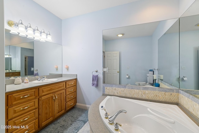 bathroom featuring vanity, tiled tub, and toilet