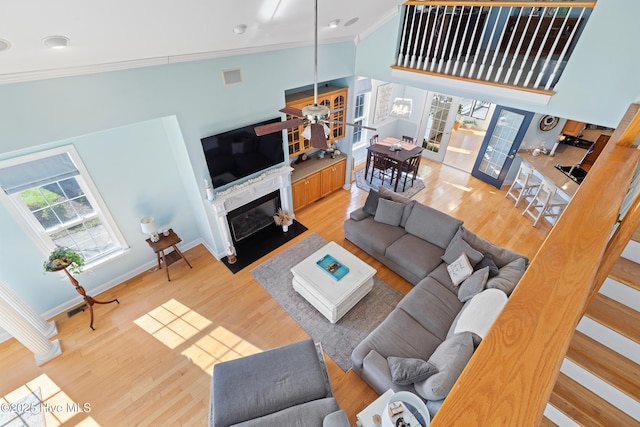 living room with crown molding, ceiling fan, light wood-type flooring, and french doors