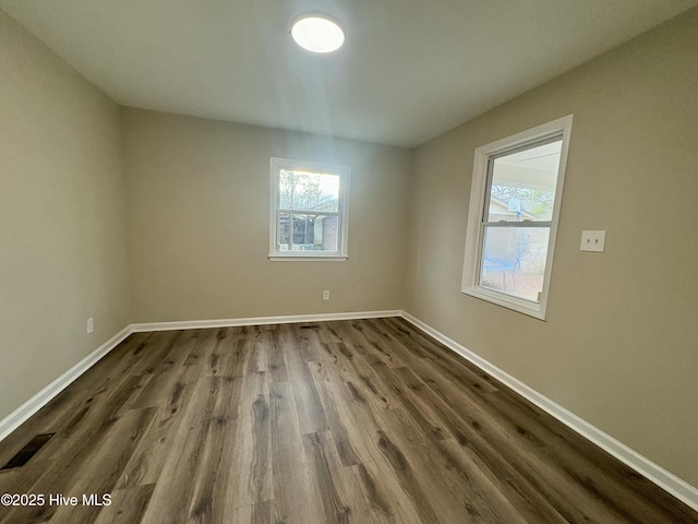 unfurnished room featuring plenty of natural light and dark hardwood / wood-style floors