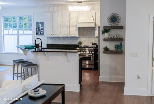 kitchen featuring a kitchen breakfast bar, stainless steel range, custom range hood, white cabinets, and dark hardwood / wood-style flooring