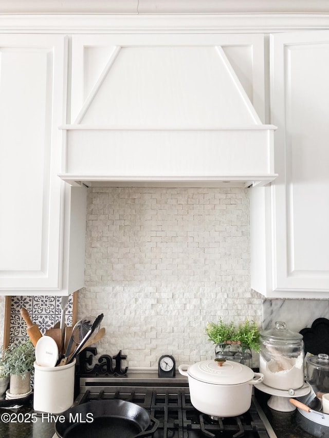 room details with premium range hood, white cabinets, and backsplash