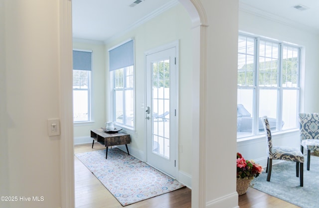 doorway with crown molding, a healthy amount of sunlight, and hardwood / wood-style floors