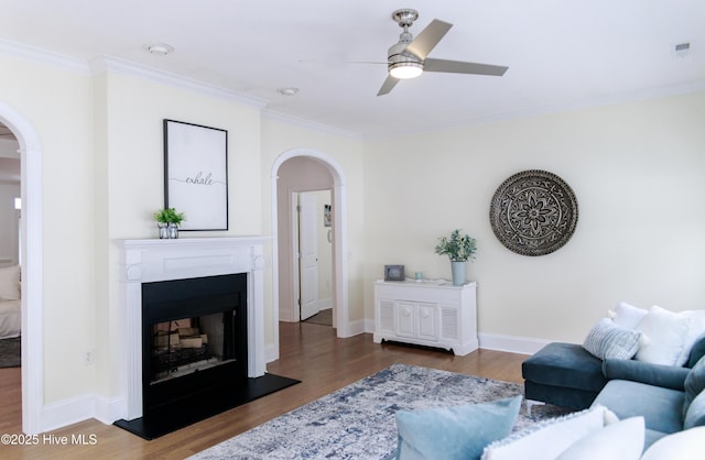 living room with wood-type flooring, ceiling fan, and crown molding