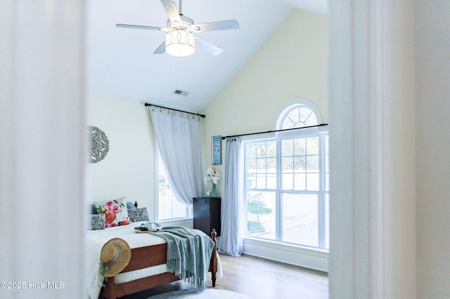 bedroom featuring multiple windows, high vaulted ceiling, and light wood-type flooring