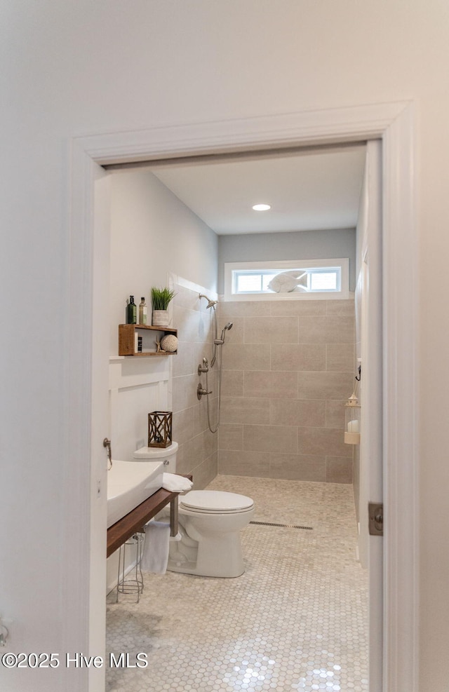 bathroom featuring tile patterned flooring, toilet, and a tile shower