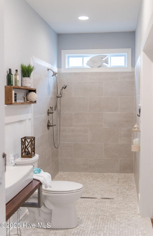 bathroom with a healthy amount of sunlight, a tile shower, and toilet