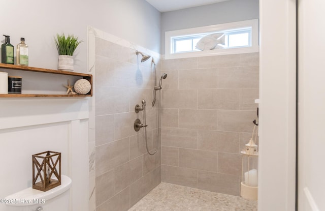 bathroom featuring a tile shower and toilet