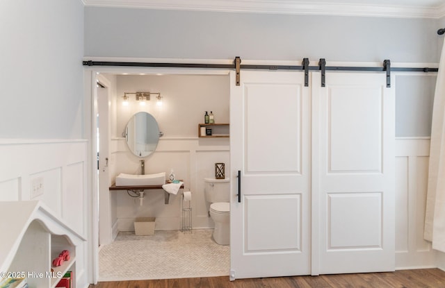 bathroom featuring ornamental molding, toilet, and hardwood / wood-style floors