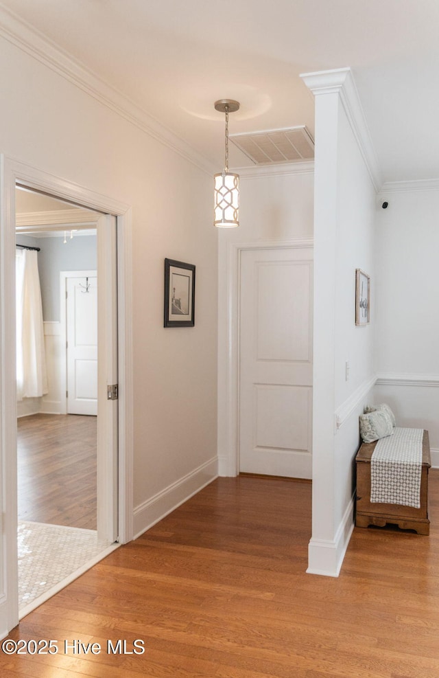 corridor with ornamental molding and hardwood / wood-style floors