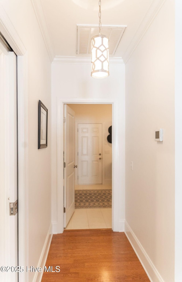 hallway with crown molding and light hardwood / wood-style flooring