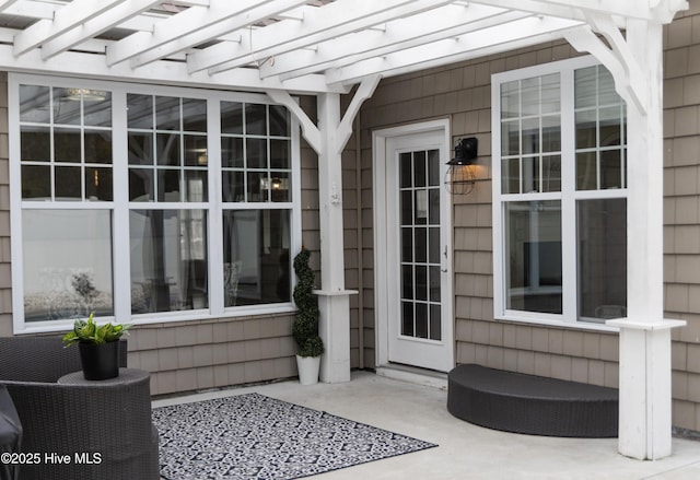 view of exterior entry featuring a pergola and a patio area