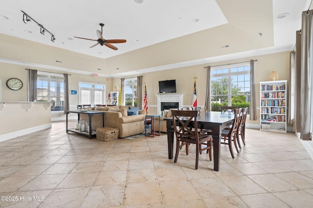 dining space featuring ceiling fan, a raised ceiling, and a wealth of natural light