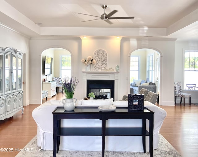 living room with hardwood / wood-style flooring, a multi sided fireplace, a raised ceiling, and ornamental molding