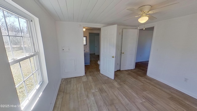 empty room featuring ceiling fan, wooden ceiling, plenty of natural light, and light wood-type flooring