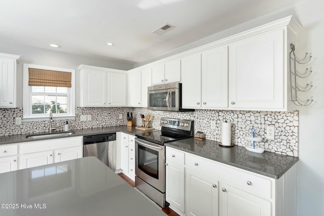 kitchen featuring stainless steel appliances, sink, white cabinets, and backsplash