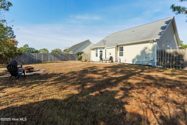 rear view of house featuring a fire pit and a lawn