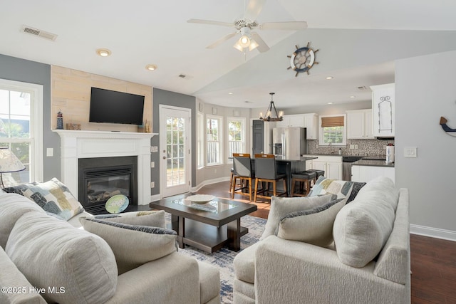 living room with ceiling fan with notable chandelier, lofted ceiling, dark hardwood / wood-style flooring, and sink