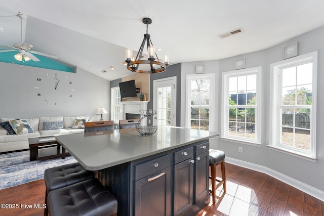 kitchen with pendant lighting, a breakfast bar area, dark hardwood / wood-style floors, a center island, and vaulted ceiling