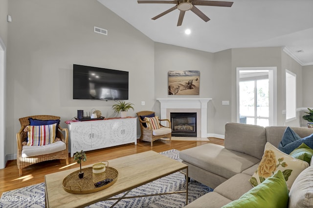 living room with ceiling fan, wood-type flooring, a fireplace, and vaulted ceiling