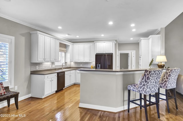 kitchen featuring built in fridge, dishwasher, white cabinets, decorative backsplash, and kitchen peninsula