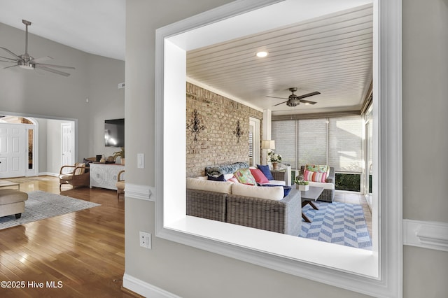 interior space featuring hardwood / wood-style flooring, ceiling fan, and a towering ceiling