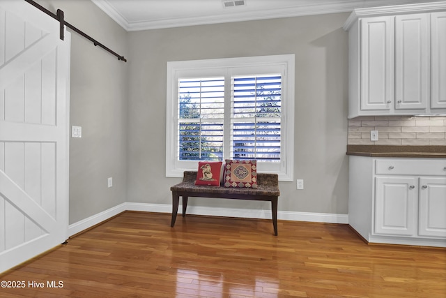 interior space featuring ornamental molding, a barn door, and light hardwood / wood-style flooring