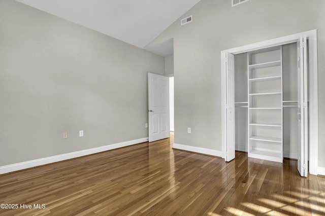 unfurnished bedroom featuring a closet, high vaulted ceiling, and dark hardwood / wood-style floors