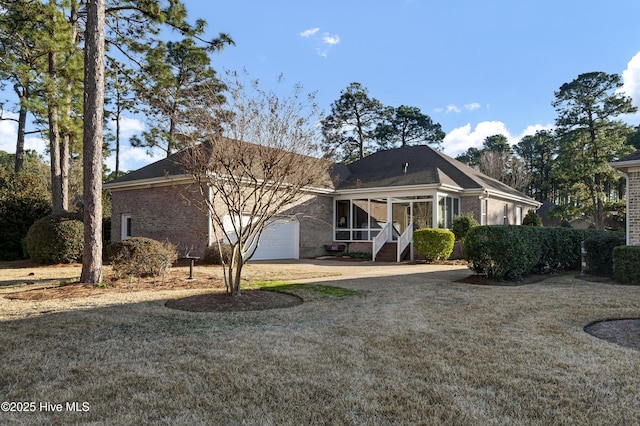 view of front of property with a garage, a sunroom, and a front yard