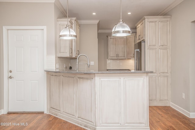 kitchen featuring high quality fridge, kitchen peninsula, hanging light fixtures, and light wood-type flooring