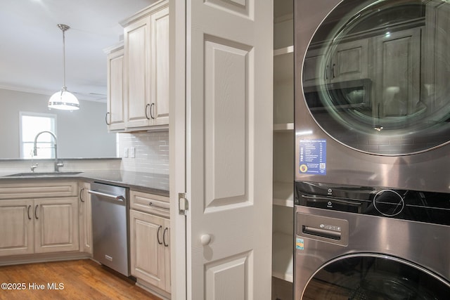 kitchen featuring sink, dishwasher, stacked washing maching and dryer, backsplash, and light wood-type flooring