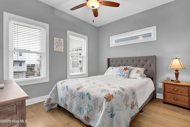 bedroom featuring ceiling fan, multiple windows, and light wood-type flooring