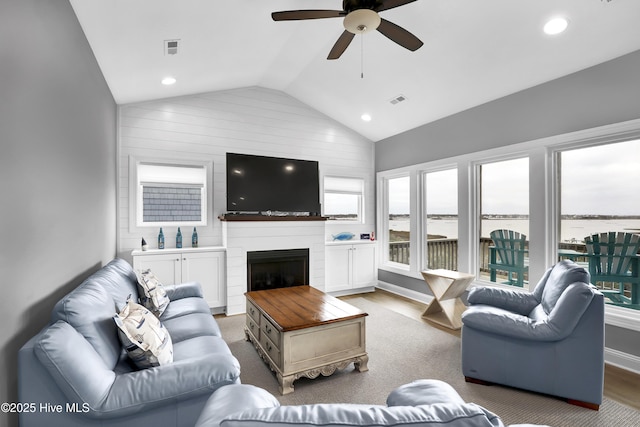 living room featuring hardwood / wood-style flooring, ceiling fan, lofted ceiling, and a fireplace