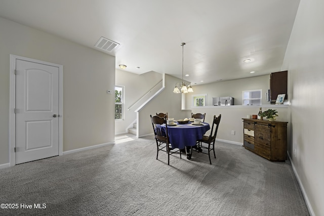 carpeted dining room featuring an inviting chandelier