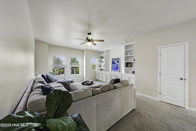 living room featuring built in shelves, ceiling fan, and carpet