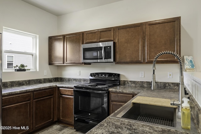 kitchen with light hardwood / wood-style flooring, black / electric stove, dark brown cabinets, and sink