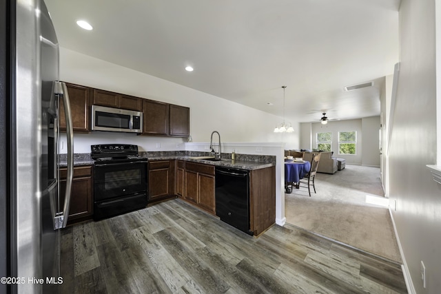 kitchen featuring sink, decorative light fixtures, wood-type flooring, and black appliances