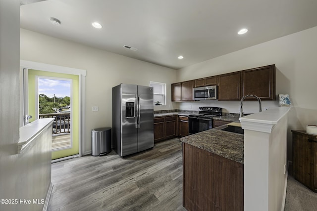 kitchen featuring sink, light hardwood / wood-style flooring, appliances with stainless steel finishes, dark brown cabinetry, and kitchen peninsula