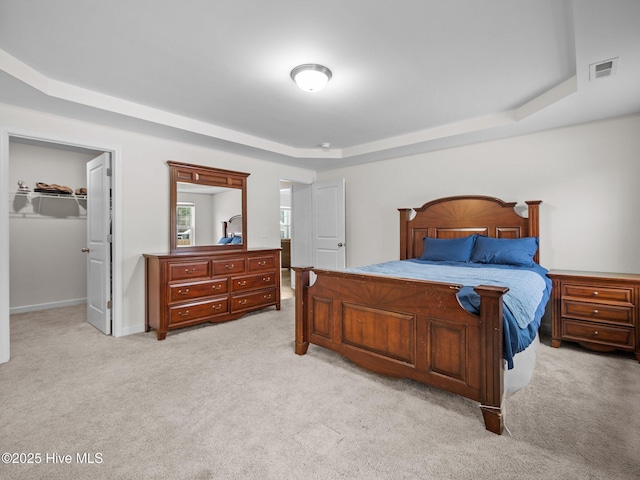 carpeted bedroom with a walk in closet, a raised ceiling, and a closet