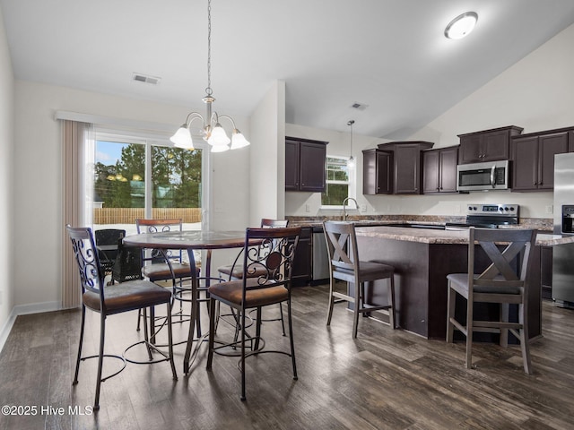 dining room featuring a notable chandelier, dark wood-type flooring, sink, and vaulted ceiling