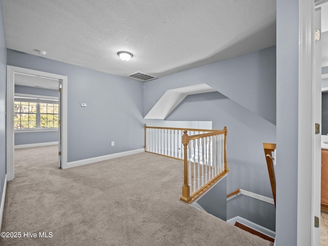 bonus room featuring light carpet and a textured ceiling