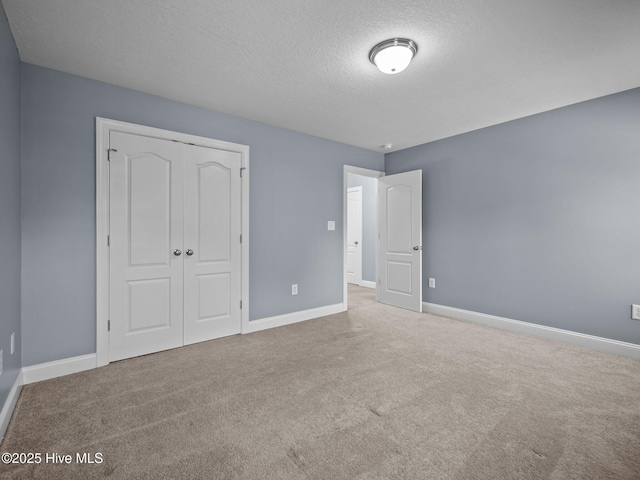 unfurnished bedroom featuring light colored carpet, a closet, and a textured ceiling