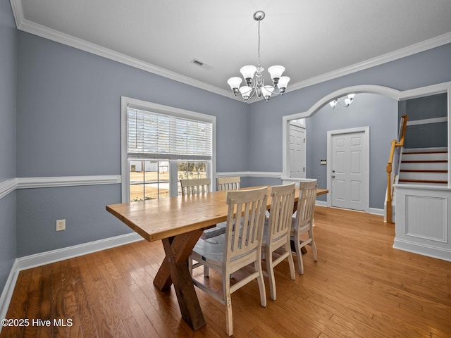 dining space with ornamental molding, light hardwood / wood-style floors, and a notable chandelier